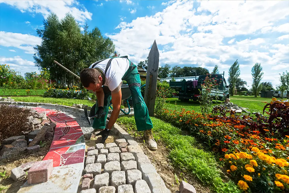 Landschaftsgärtner beim Setzen von Pflastersteinen in einer Gartenanlage